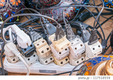 Old and damaged electric adapter power plug has many appliances are plugged outlet socket concept of risk danger overloaded current electrical. Overloaded power plugs, close up 117518559