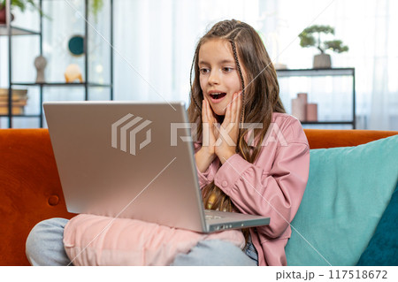Surprised happy amazed girl child using laptop computer, receive good news message celebrate win 117518672