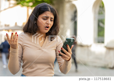 Indian woman use smartphone loses receive bad message mail news loss fail outdoors on city street Indian woman use smartphone loses receive bad message mail news loss fail outdoors on city street 117518681