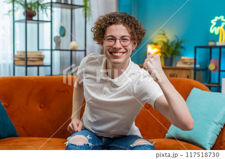 Portrait of excited young man celebrating success looking at camera good news victory watching TV Portrait of excited young man celebrating success looking at camera good news victory watching TV 117518730