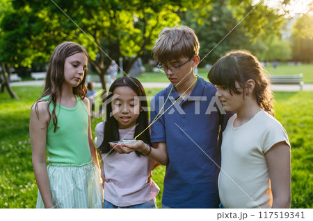 Children in outdoor sustainable educational class using compass learning orienteering in public park. 117519341