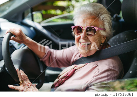 Cool senior woman in sunglasses driving car alone, enjoying car ride. Safe driving for elderly adults, older driver safety. Cool senior woman in sunglasses driving car alone, enjoying car ride. Safe driving for elderly adults, older driver safety. 117519361