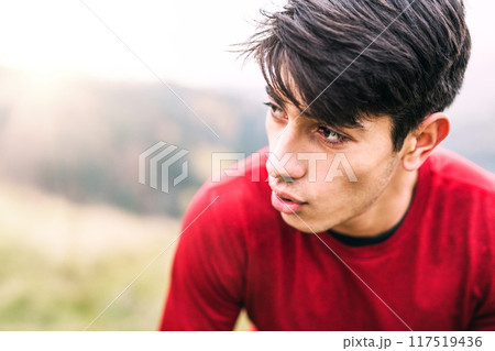 Male runner resting after jog in nature on dirt running trail, enjoying view. Morning running training for young man. Male runner resting after jog in nature on dirt running trail, enjoying view. Morning running training for young man. 117519436