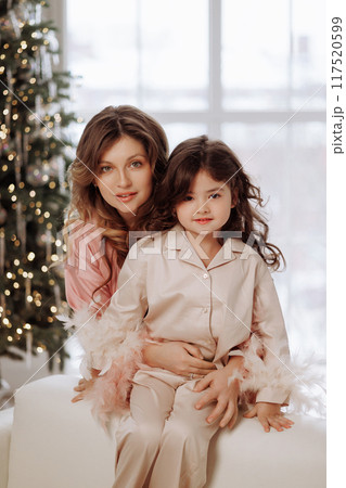 A woman and a child are posing for a picture in a room with a Christmas tree A woman and a child are posing for a picture in a room with a Christmas tree 117520599