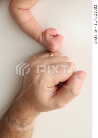 Dad and newborn baby boy son keep their hands in a fist, small and big fists. Father and son, the first boxing punch. Dad and newborn baby boy son keep their hands in a fist, small and big fists. Father and son, the first boxing punch. 117521682