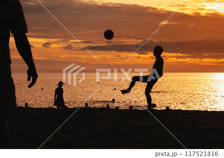 Silhouette of an Asian male player with a ball playing traditional beach football on beach by the sea at sunrise 117521816