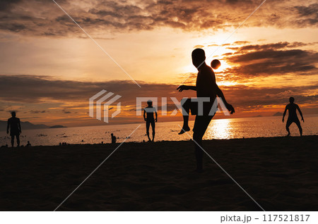 Silhouettes of Asian men ball players playing traditional beach soccer sepak takraw by sea in summer at sunrise 117521817