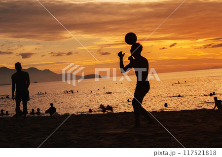 Silhouettes of Asian men ball players playing traditional beach soccer sepak takraw by sea in summer at sunrise 117521818
