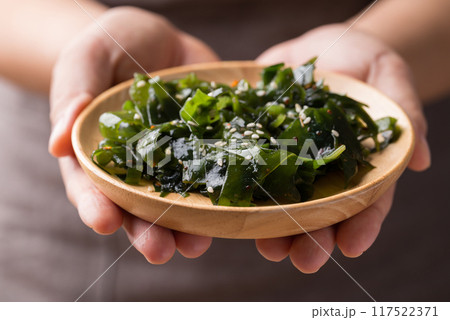 Wakame seaweed or sea mustard salad on wooden bowl holding by woman hand, Healthy eating Wakame seaweed or sea mustard salad on wooden bowl holding by woman hand, Healthy eating 117522371