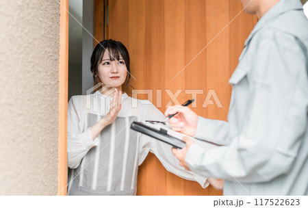 訪問営業・セールスに来た作業着姿の男性を玄関で拒否する主婦 訪問営業・セールスに来た作業着姿の男性を玄関で拒否する主婦 117522623