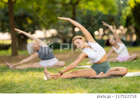 Girl participating in outdoor yoga session in summer park 117522718