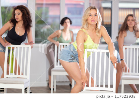 Group of girls unleash their energy and dance passionately near a chair in high heels in a dance studio. His powerful moves combined with elegance of high heels Group of girls unleash their energy and dance passionately near a chair in high heels in a dance studio. His powerful moves combined with elegance of high heels 117522938