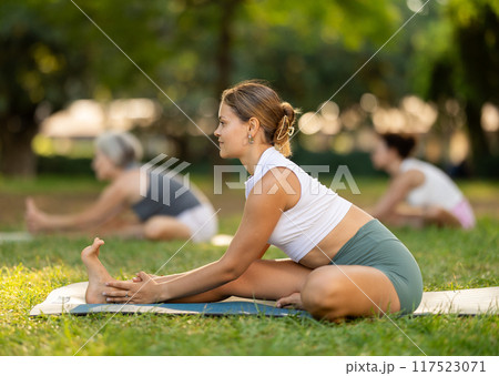 Girl participating in outdoor yoga session in summer park Girl participating in outdoor yoga session in summer park 117523071