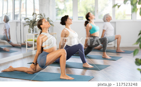 Young woman doing pilates in group in studio 117523248