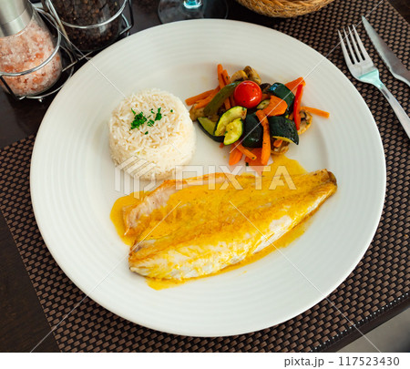 Sea bass fillet with curry sauce and basmati rice Sea bass fillet with curry sauce and basmati rice 117523430