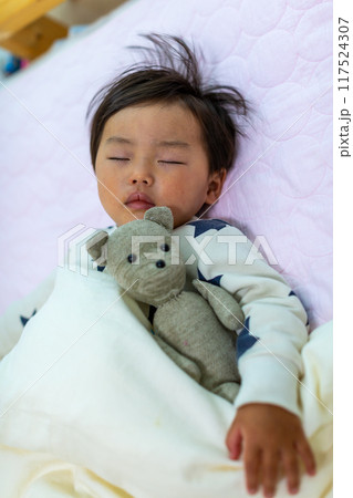 靴下ぬいぐるみを抱いて眠る2歳幼児の寝顔アップ 117524307
