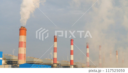 Power stations manufacturing electrical industrial plant. Electric power building refinery engineering smog steam smokestack. Lignite electricity chimneys release pollution in industry plant blue sky Power stations manufacturing electrical industrial plant. Electric power building refinery engineering smog steam smokestack. Lignite electricity chimneys release pollution in industry plant blue sky 117525050