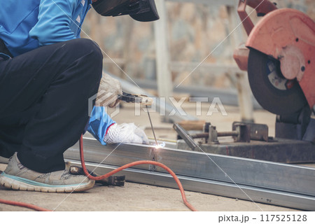 Construction Worker hands using Welding machinery iron metal sparking. Men hands wear protective glove Hot flame metal work cutting fire iron workshop. Locksmith use Welding machine cut metal process Construction Worker hands using Welding machinery iron metal sparking. Men hands wear protective glove Hot flame metal work cutting fire iron workshop. Locksmith use Welding machine cut metal process 117525128