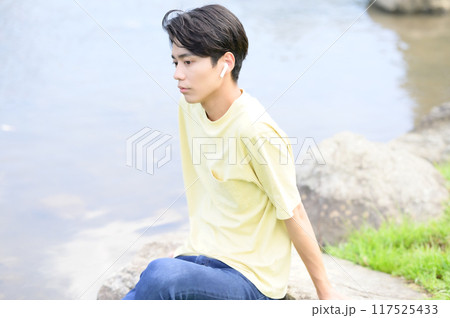 夏の水辺で涼んで音楽を聴く若い男性 夏の水辺で涼んで音楽を聴く若い男性 117525433
