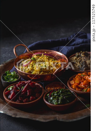 A plate featuring rice biryani and a variety of vegetarian Indian and Pakistani dishes. A plate featuring rice biryani and a variety of vegetarian Indian and Pakistani dishes. 117525749