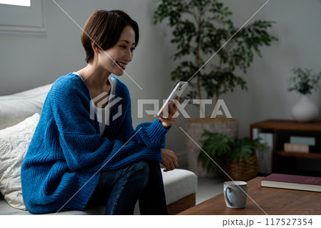 リビングでスマホを使うミドルの女性 リビングでスマホを使うミドルの女性 117527354