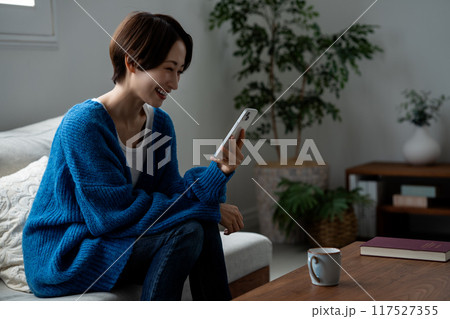 リビングでスマホを使うミドルの女性 リビングでスマホを使うミドルの女性 117527355