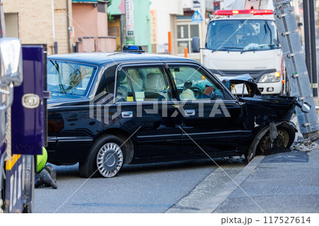 電柱に衝突し前部を大破した自動車と傾いた電柱 117527614
