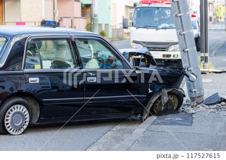 電柱に衝突し前部を大破した自動車と傾いた電柱 電柱に衝突し前部を大破した自動車と傾いた電柱 117527615