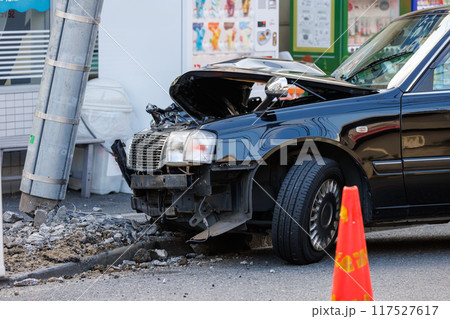 電柱に衝突し前部を大破した自動車と傾いた電柱 117527617