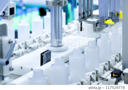 robot arm moving plastic bottle to conveyor belt of auto capping and labeling machine at cosmetic and skin care manufacturing. cosmetic industry and ai technology machinery concept. robot arm moving plastic bottle to conveyor belt of auto capping and labeling machine at cosmetic and skin care manufacturing. cosmetic industry and ai technology machinery concept. 117529778