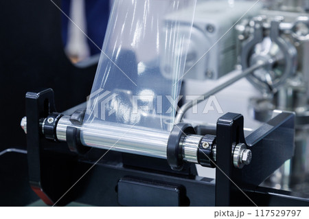 roll of plastic packaging film on the automatic packing machine in food product factory. industrial and technology concept. 117529797