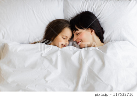 Mother and daughter sleeping cuddled together in bed Mother and daughter sleeping cuddled together in bed 117532716