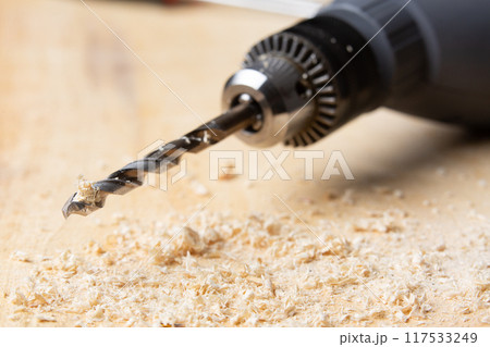 drill perched on a wooden board 117533249