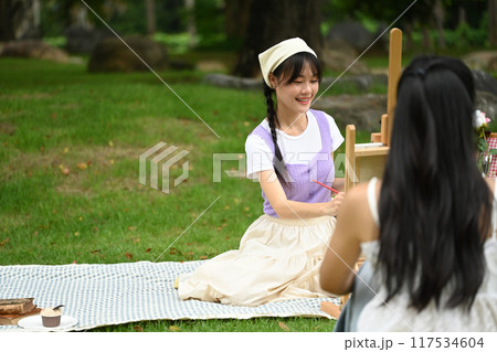Happy young asian female friends drawing and enjoying a leisurely activity together in the park 117534604