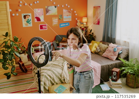 High angle view of teen influencer with disability wearing y2k casual clothes turning on smartphone camera to record content 117535269