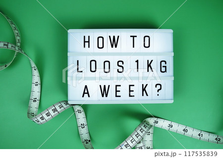 How to loos 1 KG a Week? letterboard text on LED Lightbox and Measuring tape on green background, Healthcare concept How to loos 1 KG a Week? letterboard text on LED Lightbox and Measuring tape on green background, Healthcare concept 117535839