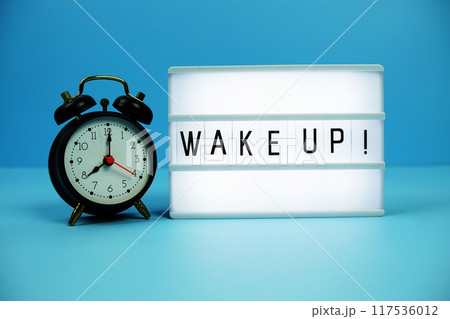 Wake Up! letterboard text on LED Lightbox and alarm clock on blue background 117536012