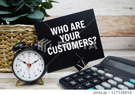 Who are your customers? text with alarm clock and calculator on wooden background, Business concept 117536058