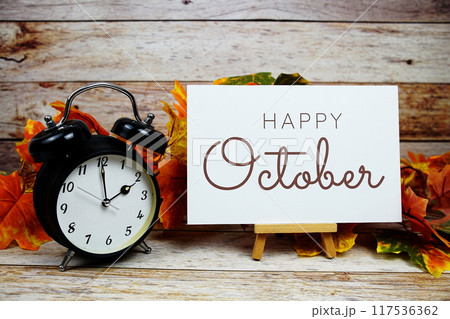 Happy October text with alarm clock and maple leaf decoration on wooden background 117536362
