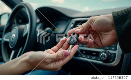 Man woman gets the car key from seller - satisfied - trade closed - new car in the background. Concept of buying a vehicle, auto business. 117536397
