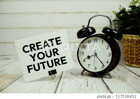 Create Your Future text on paper card with alarm clock on wooden background Create Your Future text on paper card with alarm clock on wooden background 117536452