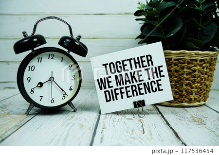 Together We Make The Difference text on paper card with alarm clock on wooden background 117536454