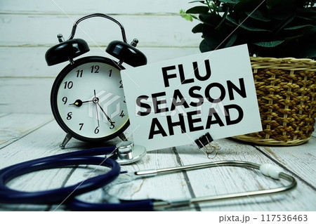 Flu Season Ahead text on paper card with alarm clock and stethoscope on wooden background Flu Season Ahead text on paper card with alarm clock and stethoscope on wooden background 117536463