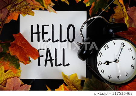 Hello Fall text with alarm clock and maple leaf decoration on wooden background 117536465