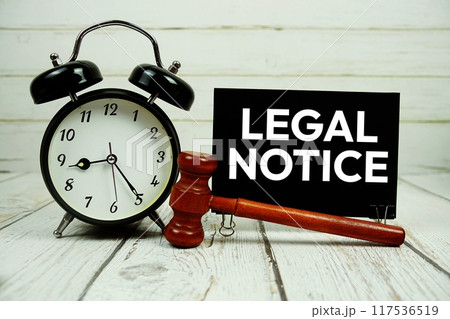 Legal Notice text on paper card with alarm clock and wooden judge gavel on wooden background 117536519