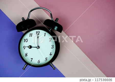 Alarm clock top view on purple and pink geometric background Alarm clock top view on purple and pink geometric background 117536606