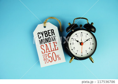 Top view of Cyber Monday Sale text on tag sale with black alarm clock flat lay on blue background 117536786