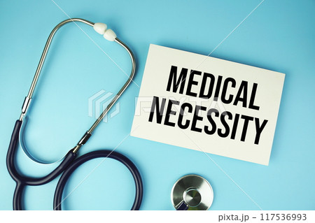 Medical Necessity text on paper card with stethoscope top view on blue background Medical Necessity text on paper card with stethoscope top view on blue background 117536993