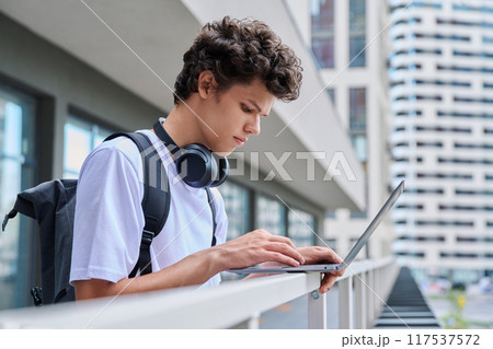 Young handsome male using laptop computer, modern city skyscrapers background 117537572