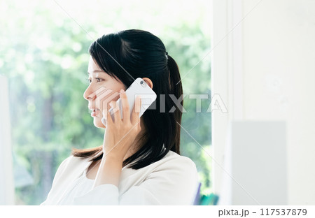 資料を手にスマホで通話する女性 資料を手にスマホで通話する女性 117537879